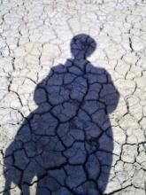 The shadow of a person on cracked mud